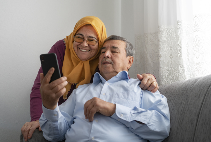 Elderly Muslim Couple looking at a smartphone together.