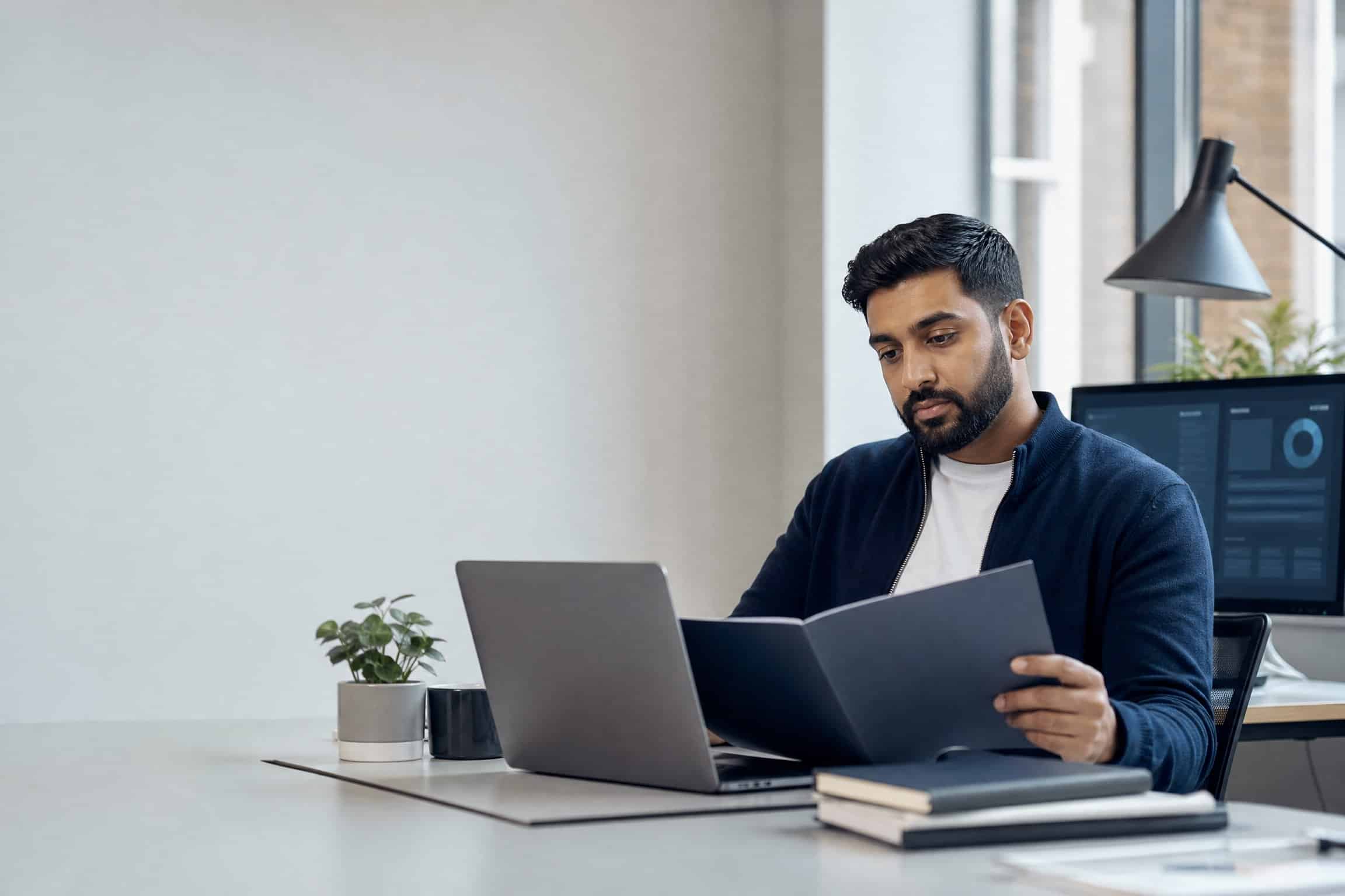 Muslim tech entrepreneur reviewing a business continuity plan beside a laptop in a modern office